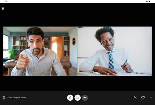 A team of diverse professionals in a bright office collaborating on a large touchscreen showing a Microsoft Teams meeting